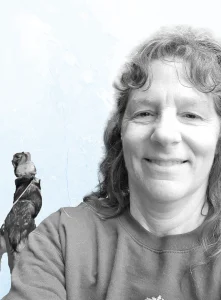 Heidi Sheldon, a woman smiling with a bird on her shoulder